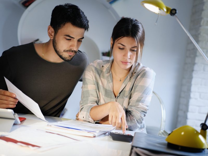 Young couple reviewing invoices and doing family business plan. Concept of money and economic problem for man and woman living together